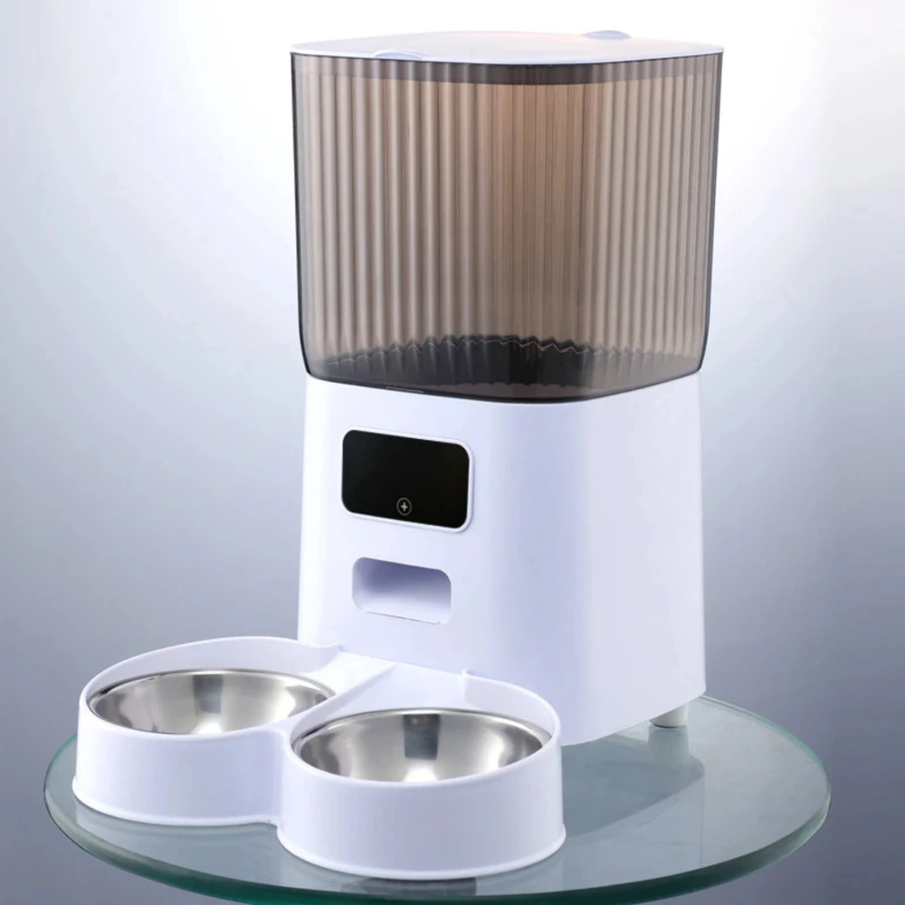 Distributeur croquette automatique blanc avec deux gamelles inox vides sur plateau verre