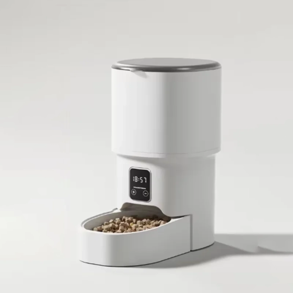 Distributeur croquette programmable blanc avec écran LCD affichant 18h57 et gamelle remplie de croquettes
