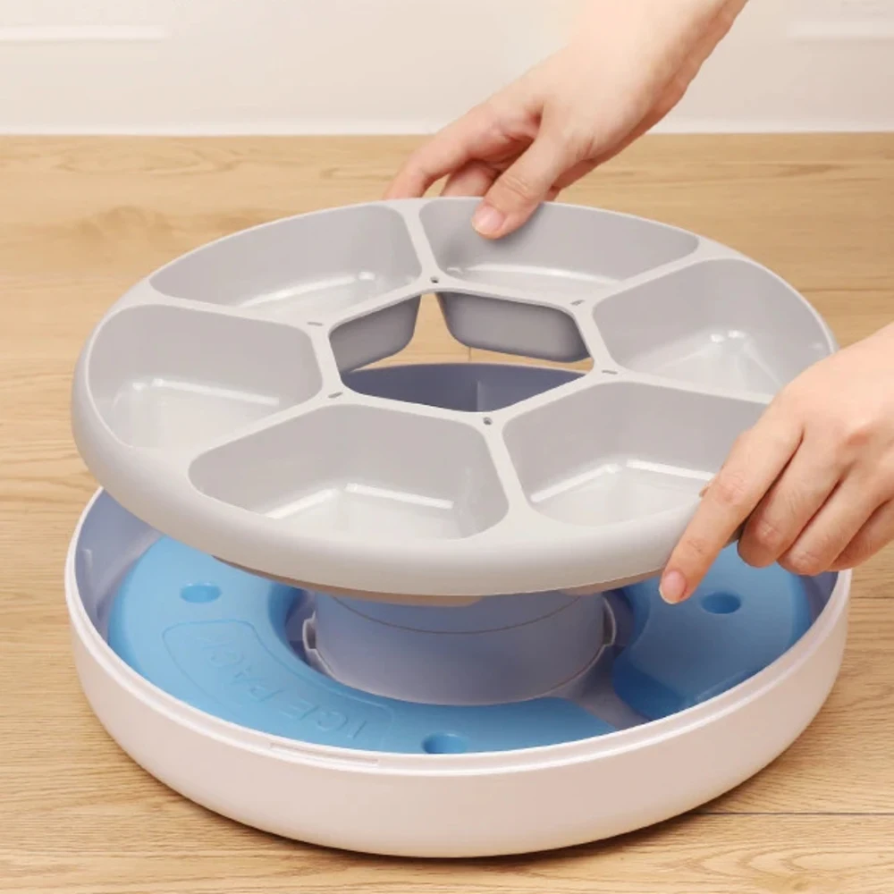 Mains séparant le plateau repas extractible à six compartiments du socle réfrigérant bleu