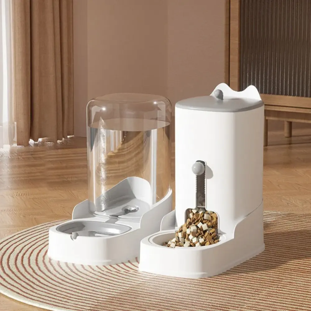 Distributeur double croquettes et eau pour chat posé sur tapis, coloris gris et blanc